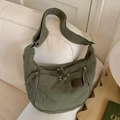 Olive green canvas hobo bag with multiple pockets and wide strap on white sofa - Green