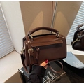 Dettaglio borsa in pelle sintetica marrone scuro con finiture dorate e riflesso a specchio - caffè