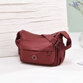 Detailed close-up of water-resistant burgundy nylon crossbody bag with textured strap - Red