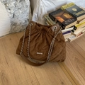 Makroaufnahme der braunen gesteppten Wildleder-Eimertasche mit Silberkette und Logo - Braun