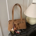 Detail of tan faux leather shoulder bag with decorative strap buckle and plush bear charm - With Charm / Brown