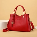 Detail of red lychee leather handbag with gold hardware and treble clef metal accents - Red