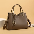 Detail of brown pebbled leather shoulder bag with gold hardware and key charms - Coffee Brown