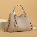 Detail of beige lychee leather bucket bag with gold hardware and musical note charms - Beige Apricot