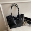 Black leather tote bag with metal buckle detail shown in a stylish study setting - No Pendant / Black