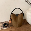 Detalle de bolso cubo en ante marrón con asa negra y colgante de estilo bohemio - Marrón