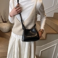 Borsa a secchiello in pelle nera con logo goffrato indossata a tracolla da una modella - Nero