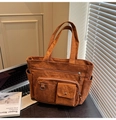 Dettaglio macro della borsa tote in velluto a coste marrone con focus su trama e tasche - Marrone