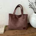 Bolso tote grande minimalista de ante marrón con logo redondo en un banco de madera - Marrón