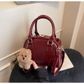 Detail of burgundy glossy handbag with MKXQ 2UD embossing and a brown teddy bear charm - With Charm / Burgundy