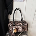 Detalle de bolso de leopardo con asas negras y colgante de caballo sobre maleta plateada - Estampado de Leopardo Con Colgante
