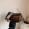 Retro coffee brown cylinder bag with geometric patterned strap on a minimalist background - Brown