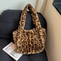 Grande borsa tote alla moda in finta pelliccia leopardata appoggiata su un divano nero - Stampa leopardata
