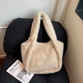 Elegante borsa tote in peluche beige con morbida finta pelliccia su una sedia nera - Cachi