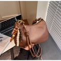 Detailed shot of brown crescent underarm bag with knotted handle and beaded tassel - Brown