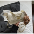 Detail of a creamy beige quilted crossbody bag with a gold lock and teddy bear charm - With Pendant / Off White