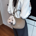 Grey textured leather crescent bag with bunny charm shown on model in modern setting - Elephant Gray with Charm