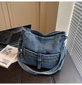 Détail du sac bandoulière en denim bleu vintage avec poches zippées et boucles métal - Bleu clair