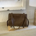 Bolso de hombro marrón oscuro retro con barra dorada sobre fondo de libros antiguos - Marrón