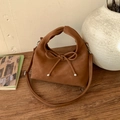 Close-up of caramel leather handbag featuring a matte bow and silver metallic accents - Brown