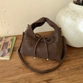 Detail of matte dark brown handbag with ribbon bow and silver metal beads on wood - Brown