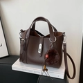Detailed view of dark brown pebbled leather bucket bag with silver lock and plush charm - Coffee with Pendant