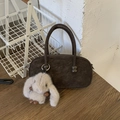 Detail der braunen Wildleder-Boston-Tasche mit flauschigem Hasen-Anhänger auf Holz - Mit Plüsch-Hasen-Anhänger / Braun