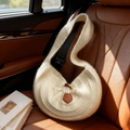 Cremeweiße Hobo-Stricktasche mit Vintage-Hornknopf auf einem braunen Autoledersitz - Cremeweiß
