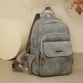 Macro detail of grey leather backpack texture and bronze metal logo with zip pockets - Gray