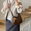 Dark brown saddle bag with vertical stitching and faux fur charm, worn by model - Beige Khaki With Charm