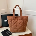 Brown quilted tote bag with diamond stitching on a white lace tablecloth - Brown