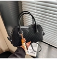 Detail of black woven leather handbag showing texture and wooden bead pendant accessory - Black