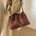 Brown quilted leather tote bag with gold chain strap shown on a beige wool coat - Brown