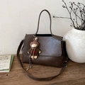 Macro detail of brown lychee grain leather tote bag with a cute bear charm and straps - With Charm / Brown