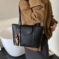 Borsa tote nera martellata con ciondolo a stella e chiusura a scatto indossata a spalla - Con Ciondolo / Nero