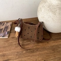Detail of a brown polka dot underarm bag with plush charm on a wooden texture background - Brown