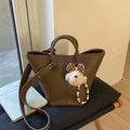 Detail of dark brown pebble leather bucket bag with cute plush puppy charm and strap - With Charm / Brown