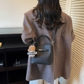 Black litchi grain leather bucket bag with silver clasp and bear charm on model - Black with Pendant