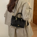 Minimalistische schwarze Leder-Eimertasche mit Fransen und goldenen Details am Model - Schwarz
