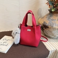 Detail of rose red lychee leather bucket bag with silver lock and plush rabbit charm - Red with Pendant