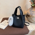 Detail of black pebbled leather bucket bag with silver twist lock and plush rabbit charm - Black with Pendant