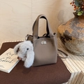 Detail of grey pebbled leather bucket bag featuring metal twist lock and plush bunny charm - Elephant Gray with Charm