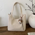 Close-up of off-white canvas tote bag with embroidery detail and plush dog charm - With Pendant / Off White