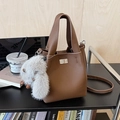 Brown lychee leather bucket bag with a plush bunny charm and adjustable strap - Brown with Pendant