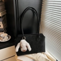 Detalle de un bolso tote negro con correa larga y un colgante de conejo de peluche gris - Con Colgante / Negro
