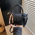 Minimalist black faux leather handbag with wooden beaded tassel and long shoulder strap - Black