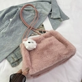 Rosa Plüsch-Beuteltasche aus Kunstfell mit weißem Anhänger auf Denim-Hintergrund - Rosa