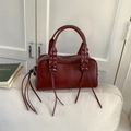 Detail of burgundy bowling bag featuring silver eyelets and long decorative leather tassels - Burgundy