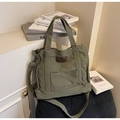 Macro detail of Army green canvas tote bag with brown leather tag and metal buckle - Green