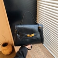 Klassieke zwarte leren crossbodytas met handvat en gouden draaisluiting op hout - Zwart